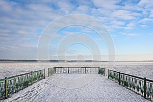 Frozen lake seen from the snowy pier on a chilly day.