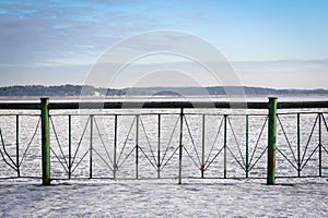 Frozen lake seen from the snowy pier on a chilly day.