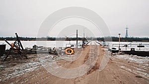 Frozen lake shore, bridge and rusted pier with boat