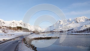 Frozen lake and snow covered mountains on road to Laukvik on the Lofoten in Norway