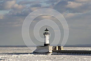 Frozen Lake Superior shoreline with lighthouse and shipping pier