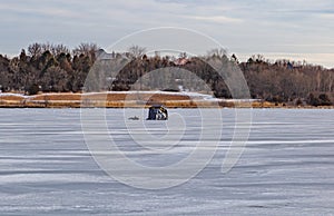 Ice fishing; Frozen lake surface in winter with ice shanty