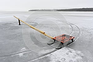 Frozen lake wih red sleigh and wtooden plank