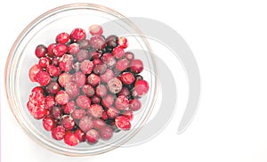 Frozen lingonberries in a glass plate on a light background