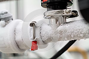 Frozen liquid nitrogen carrying pipes with a valve and black plastic lever close up in a science laboratory