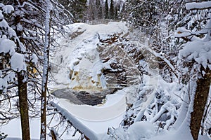 Frozen Little Manitou Falls with fresh snow during winter at Pattison State Park in Superior Wisconsin