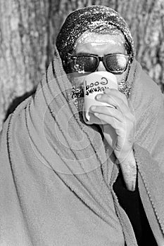 Frozen man, bearded hipster, with beard and moustache in black sunglasses covered with white frost wrapped in orange