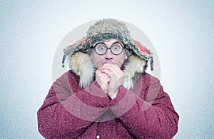 Frozen man in winter clothes and glasses warming hands, cold, snow, blizzard