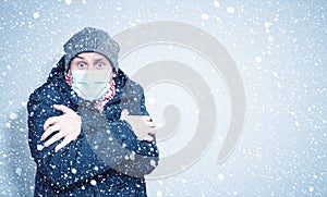 Frozen man in winter clothes on his face wearing a respirator mask to protect against the virus covid, snow around