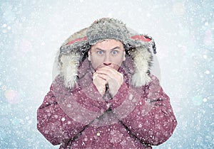 Frozen man in winter clothes warming hands, cold, snow, blizzard