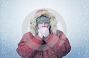 Frozen man in winter clothes warming hands, cold, snow, blizzard