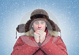 Frozen man in winter clothes warming hands, cold, snow, blizzard photo