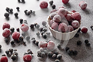 Frozen mix berries red sour cherry and black currant on gray background.