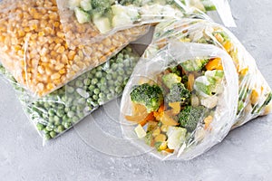 Frozen mixed vegetables in a bag on a light concrete background. Frozen food