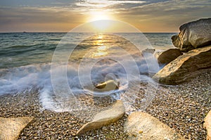 Frozen moment wave enveloping the stone on the seashore