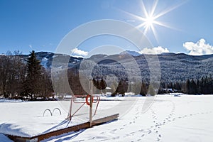 Frozen mountain lake with a sunburst on a sunny day.