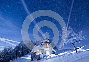 Frozen mountains cabin under a night sky filled with stars