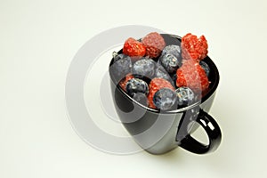 Frozen northern highbush blueberry and raspberries in black cup