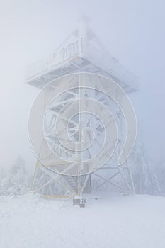 Frozen observation tower on top of a mountain in foggy winter scenery
