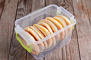 Frozen pancakes in plastic container on wooden table. Ready frozen food