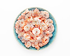 Frozen pilled prawns with ice cubes on a blue plate on a white background