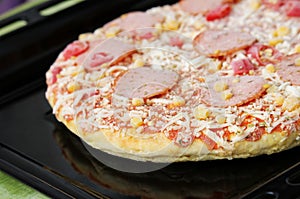 Frozen pizza with salami, cheese, corn and pepper