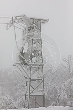 Frozen power line pylons. Hoarfrost on high voltage cables and pylons. Winter in the mountains