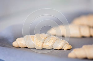 Frozen and pre-made or prefab croissants on a tin waiting to get to the oven at home, easy cooking with convenience food