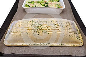Frozen puff pastry with salmon and pollock fillet with broccoli and roasted almonds in a cream sauce lying on baking paper, isolat