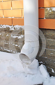 Frozen Rain Water Draining Gutter Downpipe. Gutter Spout in Winter.