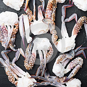 Frozen raw blue swimming crab claws, on black background, top view flat lay