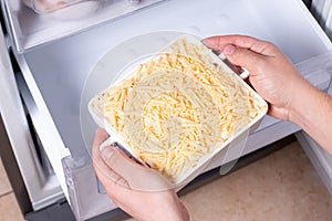 Frozen ready meals. Man`s hands are taking frozen casserole from the freezer. Concept of ready made frozen dishes and saving time