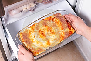 Frozen ready meals. Man`s hands are taking frozen lasagna from the freezer. Concept of ready made frozen dishes and saving time o