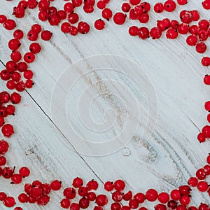 Frozen red currant on a white wooden background in the form of a frame on the edge