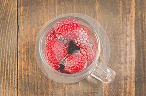 frozen red raspberry in a glass cup /frozen red raspberry in a glass cup on a wooden background, top view