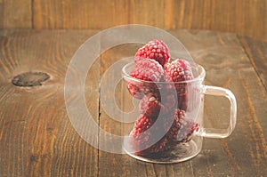 frozen red raspberry used in a glass cup/frozen red raspberry used in a glass cup on a wooden background with scopy space