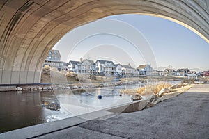 Frozen river flowing under the bridge in the middle of an inhabited area with buildings