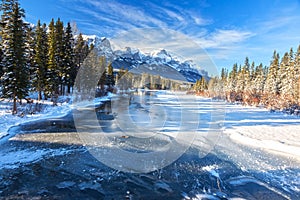 Frozen River Ice and Distant Snowy Mountain Peaks Landscape in Canadian Rockies, Banff National Park