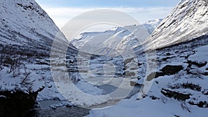 Frozen river in mountain valley on Trollstigen road in snow in Norway in autumn