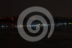 Frozen river, night and ice anglers