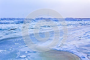 Frozen river sea on dike snow ice floes black ice