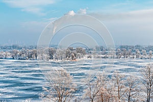 Frozen river and the smoke from the chimney in the city