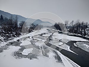 Frozen river with snow and ice in the winter season. Romania, Transylvania, Nasaud city.Winter landscape