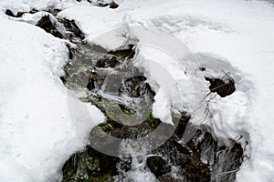 Zamrznutá rieka s prúdom vody pokrytá snehom a ľadom.