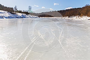 Frozen river on a sunny day. A forest grows on the shore