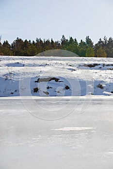 Frozen river on a sunny day. A forest grows on the shore