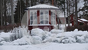 Frozen rocks and teahouse on shore of lake Siljan in Tallberg near Rattvik in Dalarna in Sweden