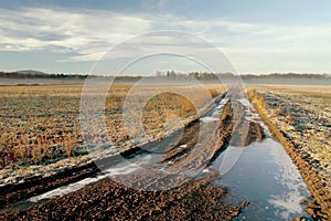 Frozen rural track at sunrise in autumn