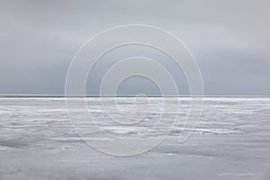 Frozen sea water and gray sky over horizon