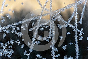 frozen shapes of snowflakes on glass against sun